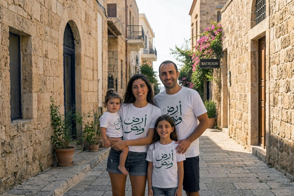 Family of four wearing matching t-shirts with Arabic text on a Lebanese street.